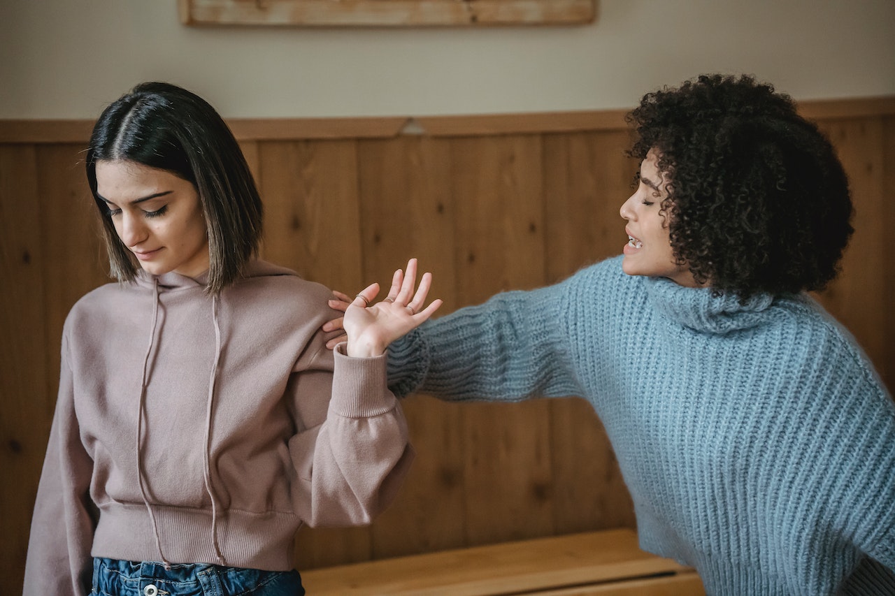 Black woman trying to talk with a woman turned with back at her.