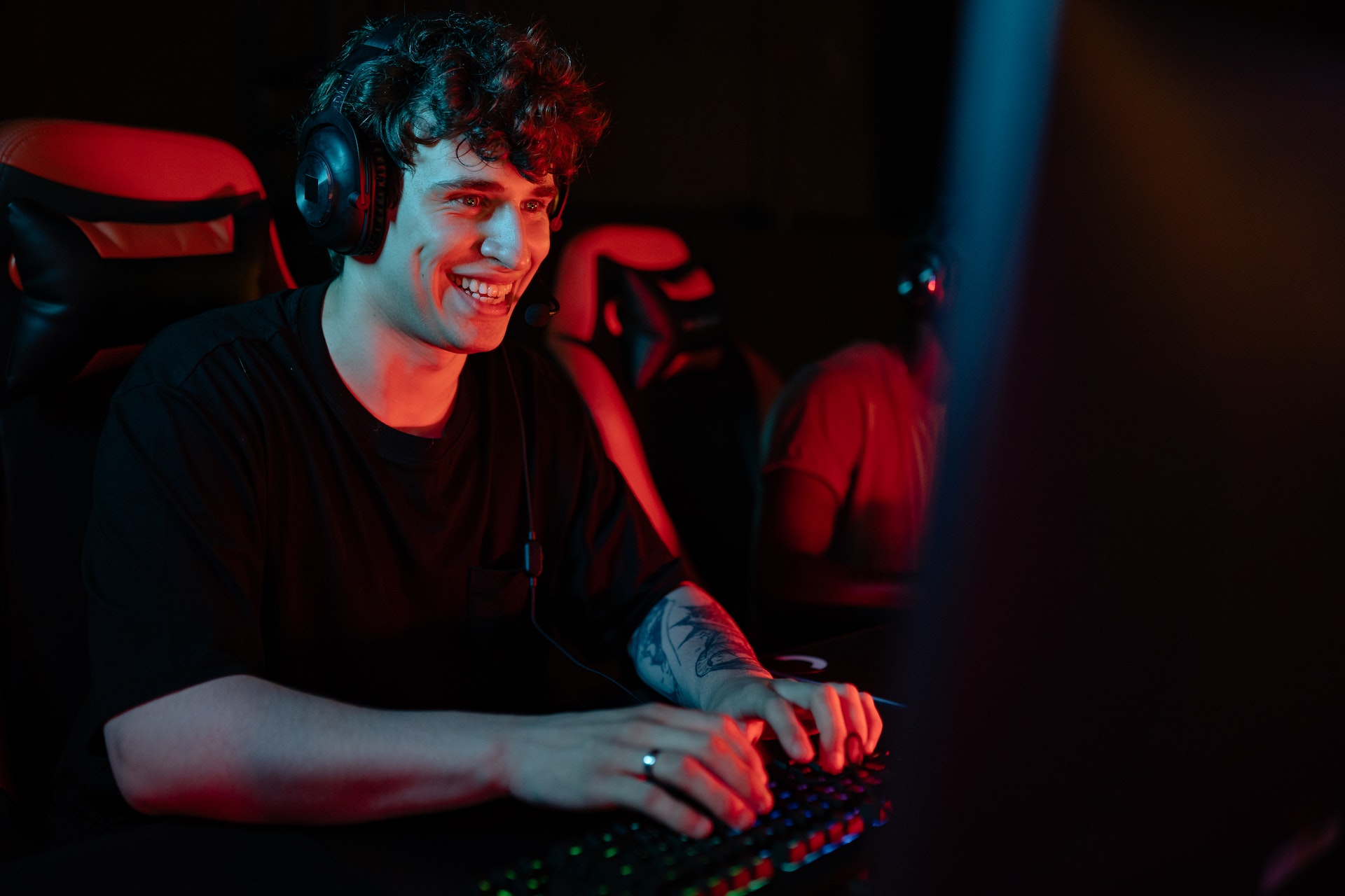 Happy man in black t-shirt playing a game on computer with headset