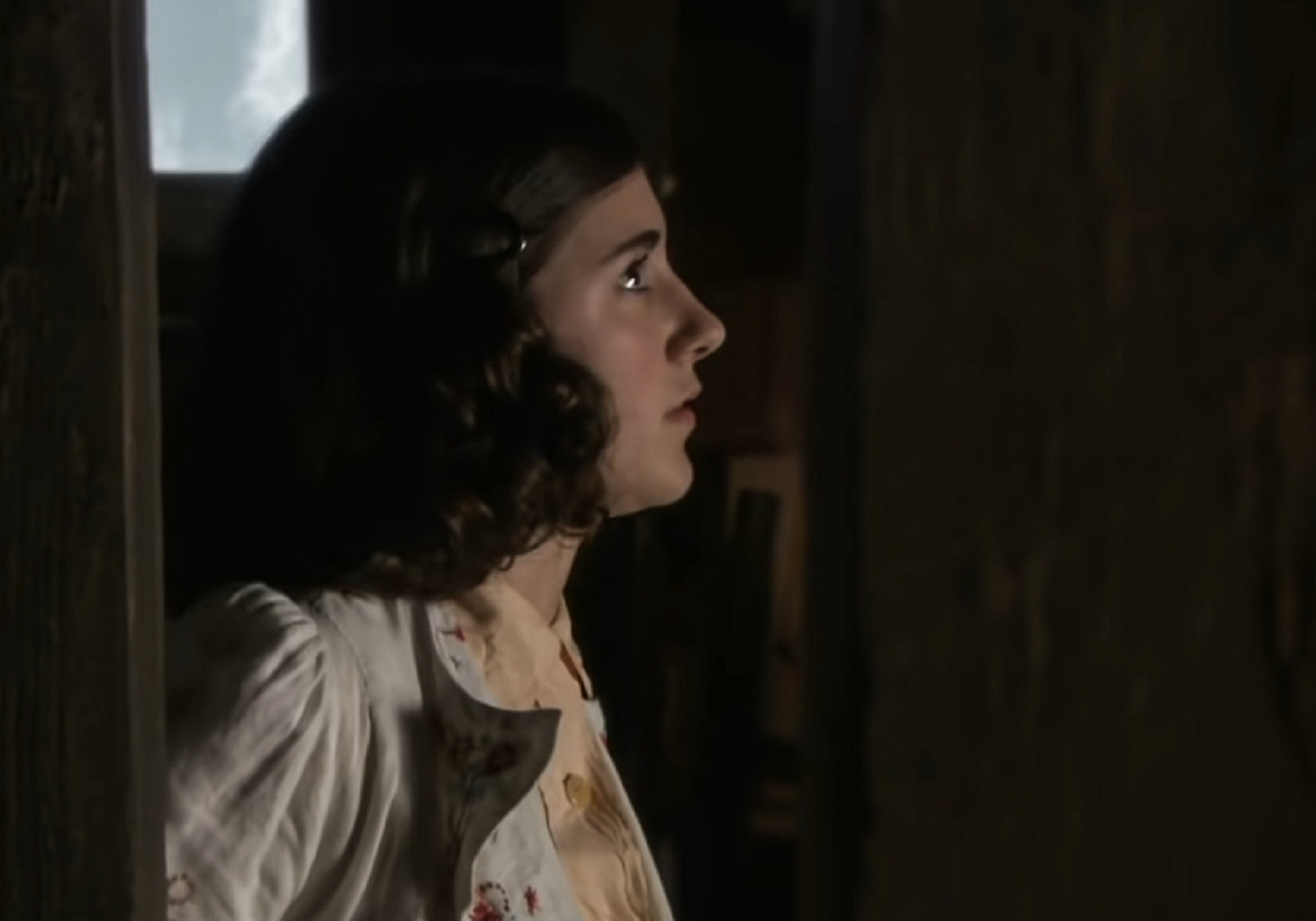 Screenshot: (Ellie Kendrick) Anne Frank with long hair wearing white shirt looking at side scared- From BBC ,The Diary Of Anne Frank (2009)