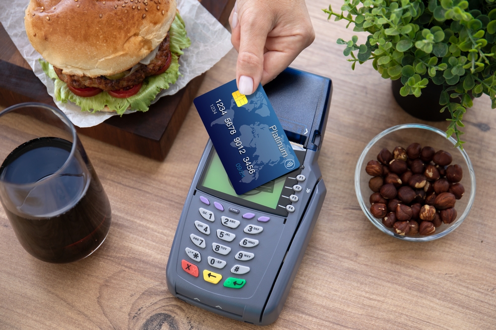 Woman hand holding plastic card paying for a burger