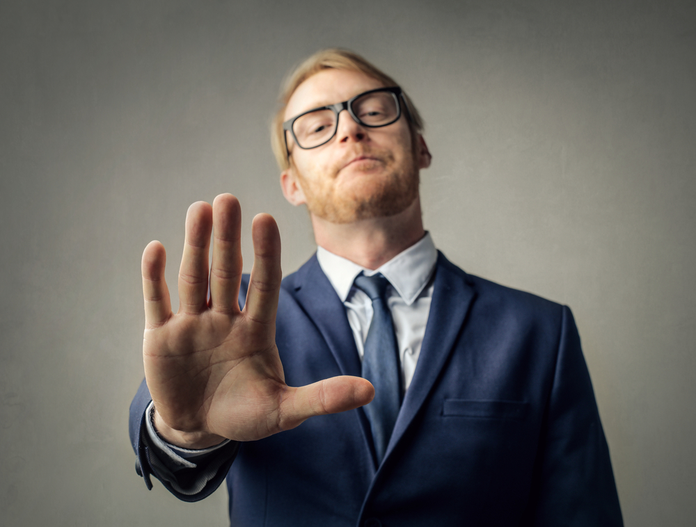 Young businessman in suit stopping someone with a gesture of his hand