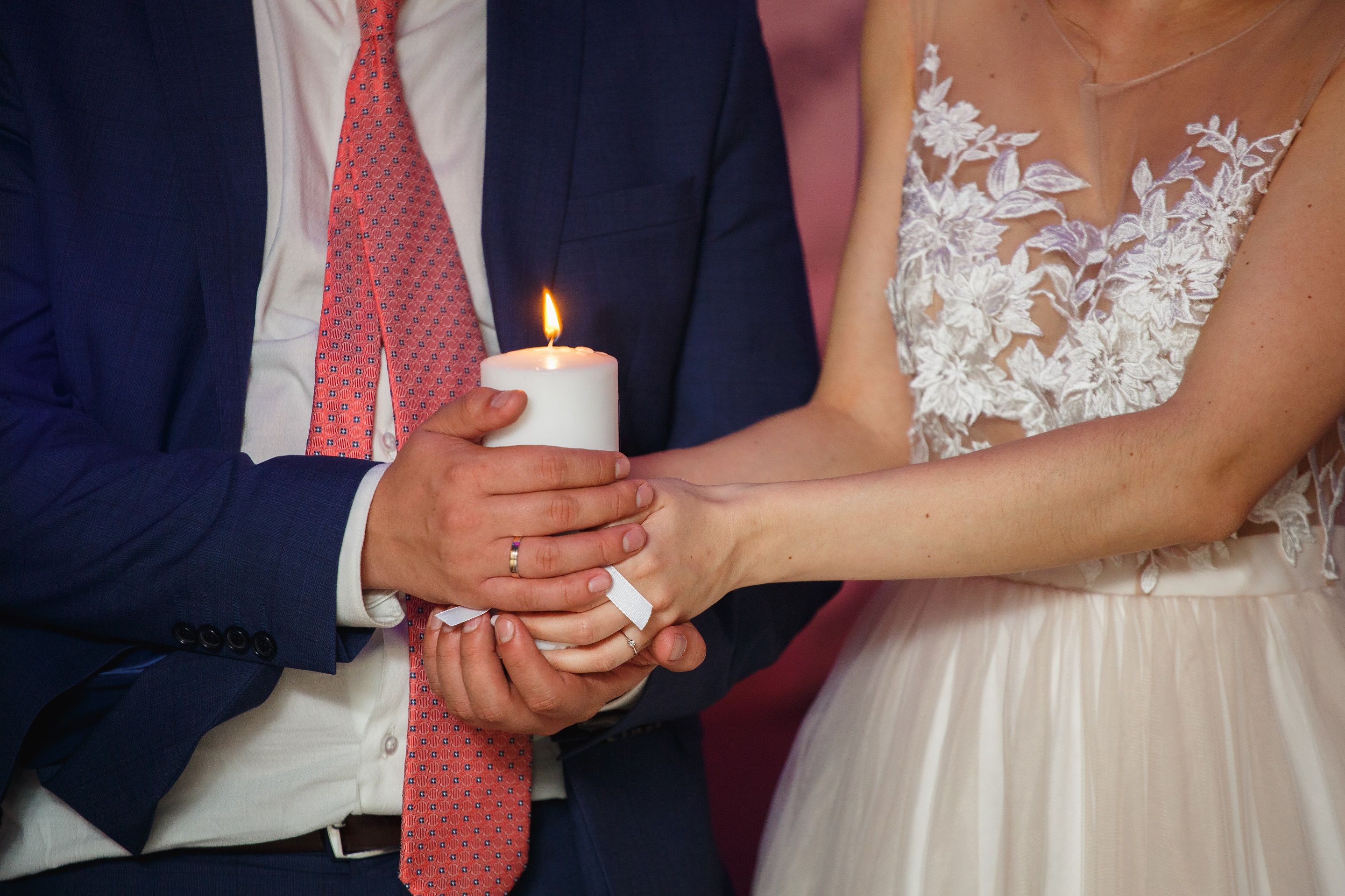Bride and groom holding a white candle together.
