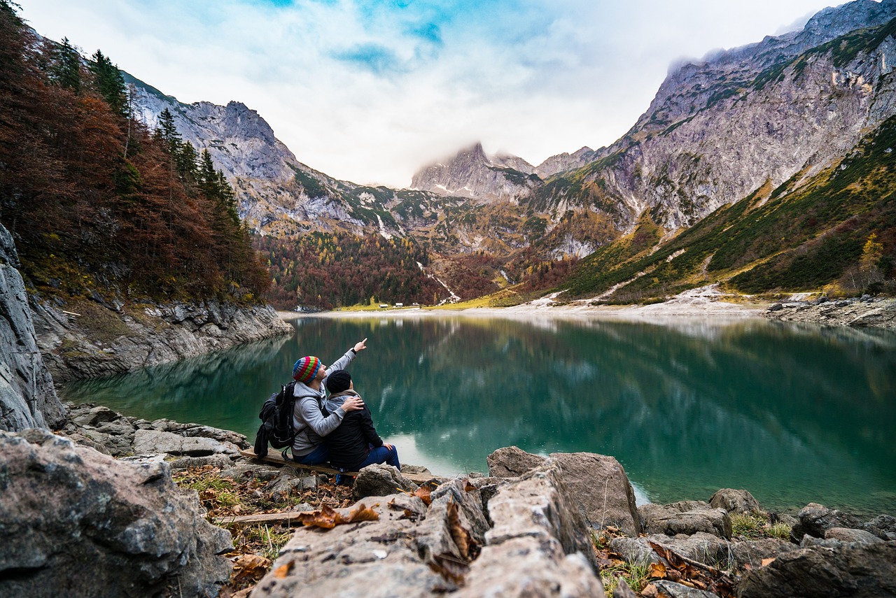 Couple hiking on mountain sitting at a lake having rest