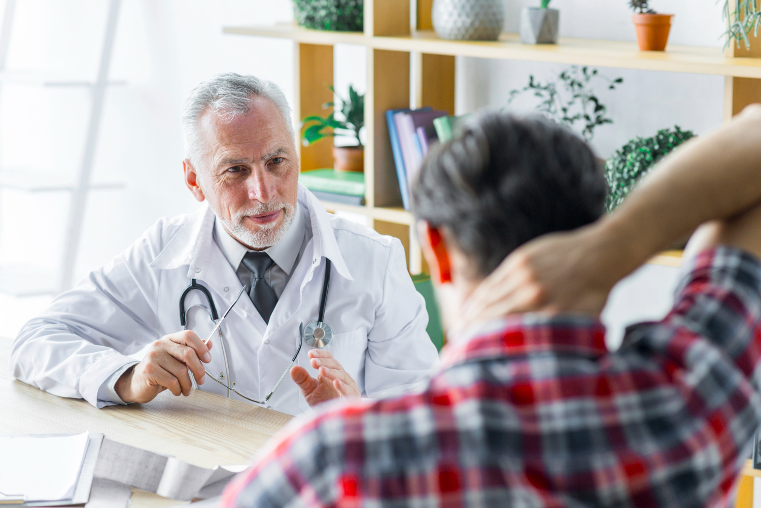Male patient is talking with male doctor in his office.