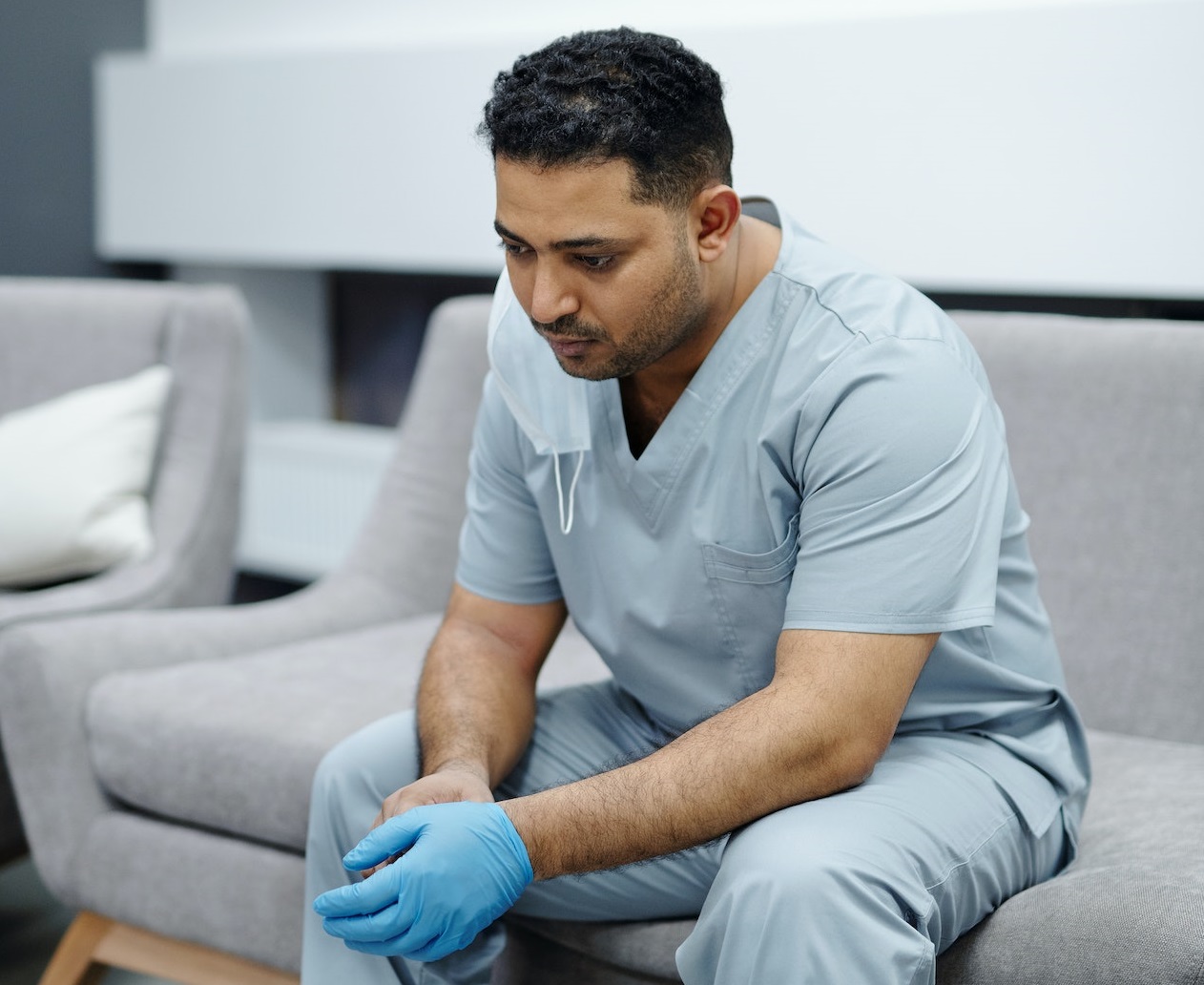 A doctor is resting on the sofa,looking tired.