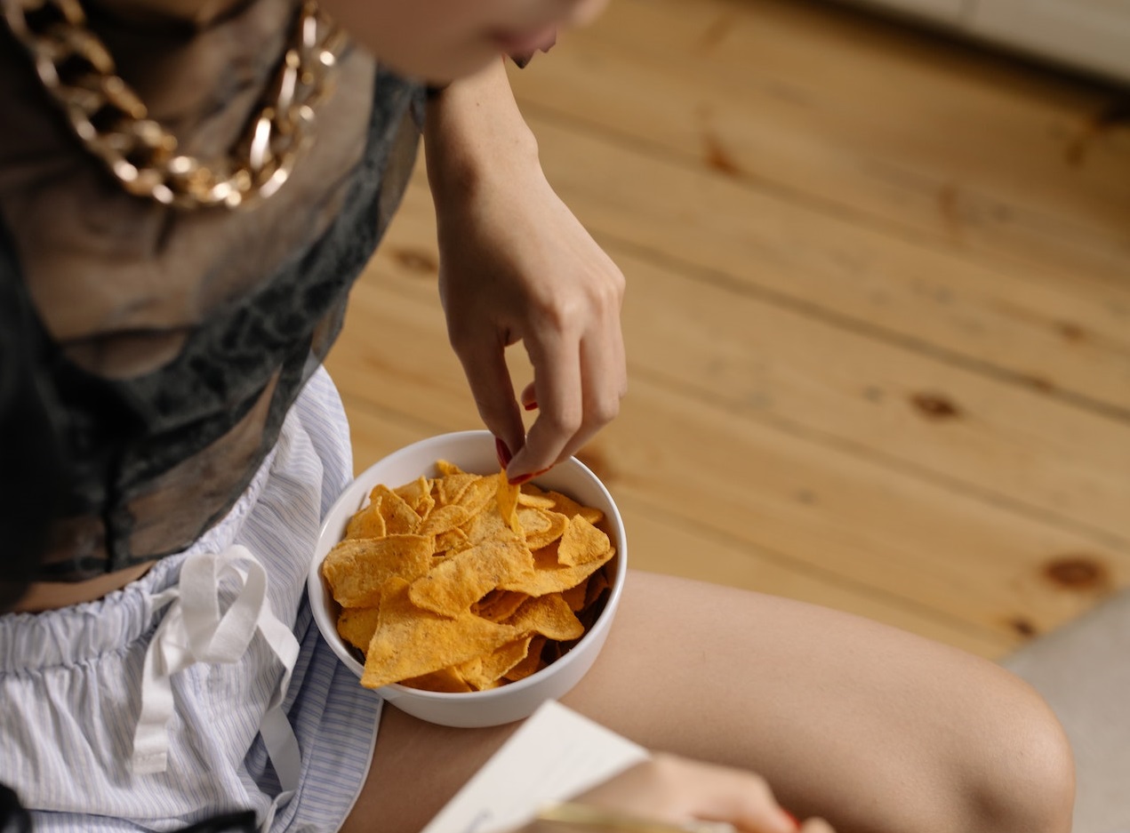 Woman is eating chips.