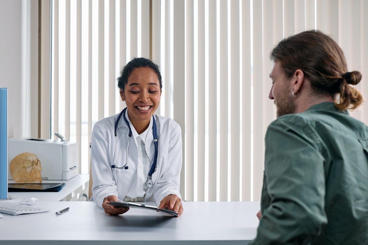 Man is talking with female doctor in her office.
