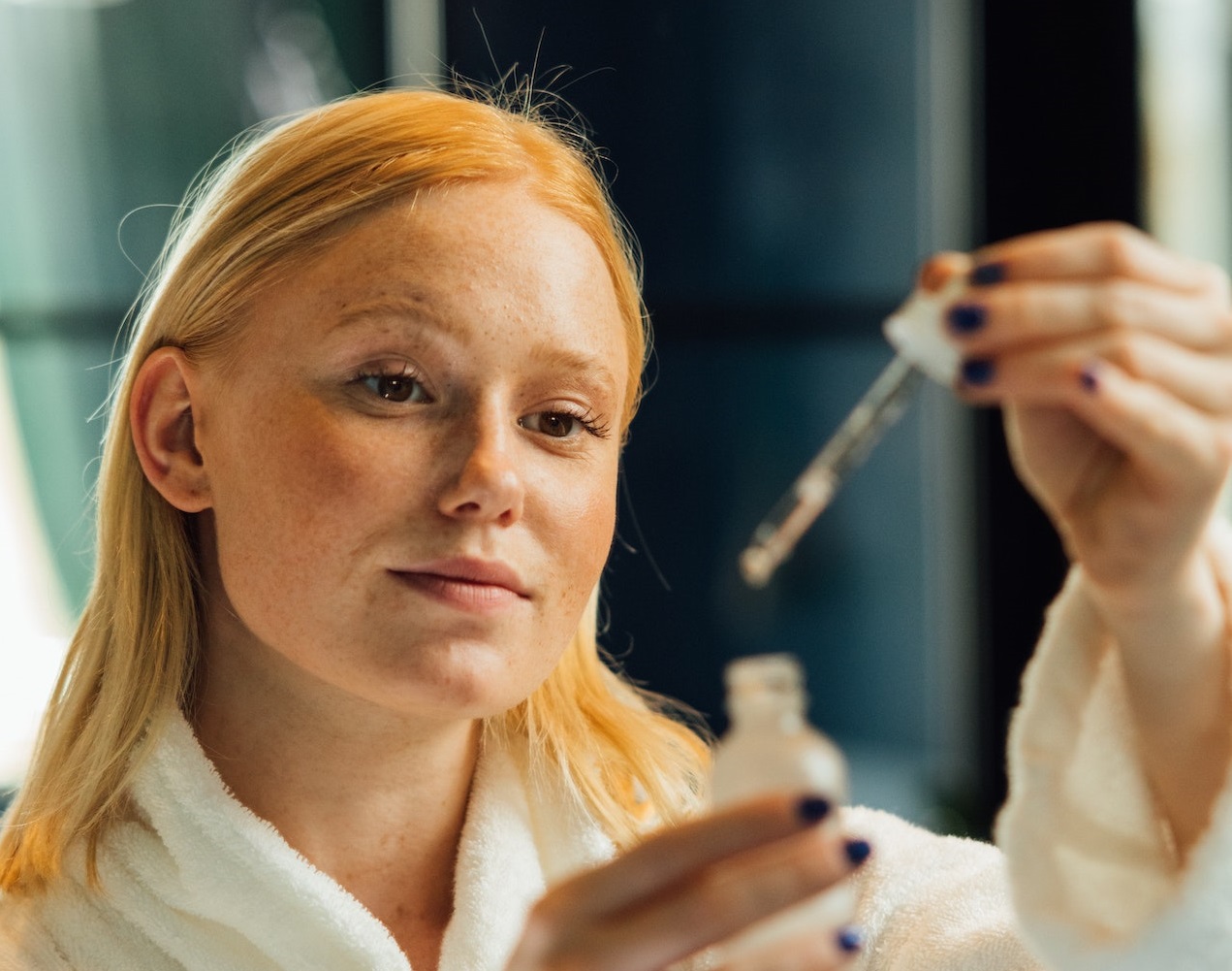 Young woman is holding bottle of drops.