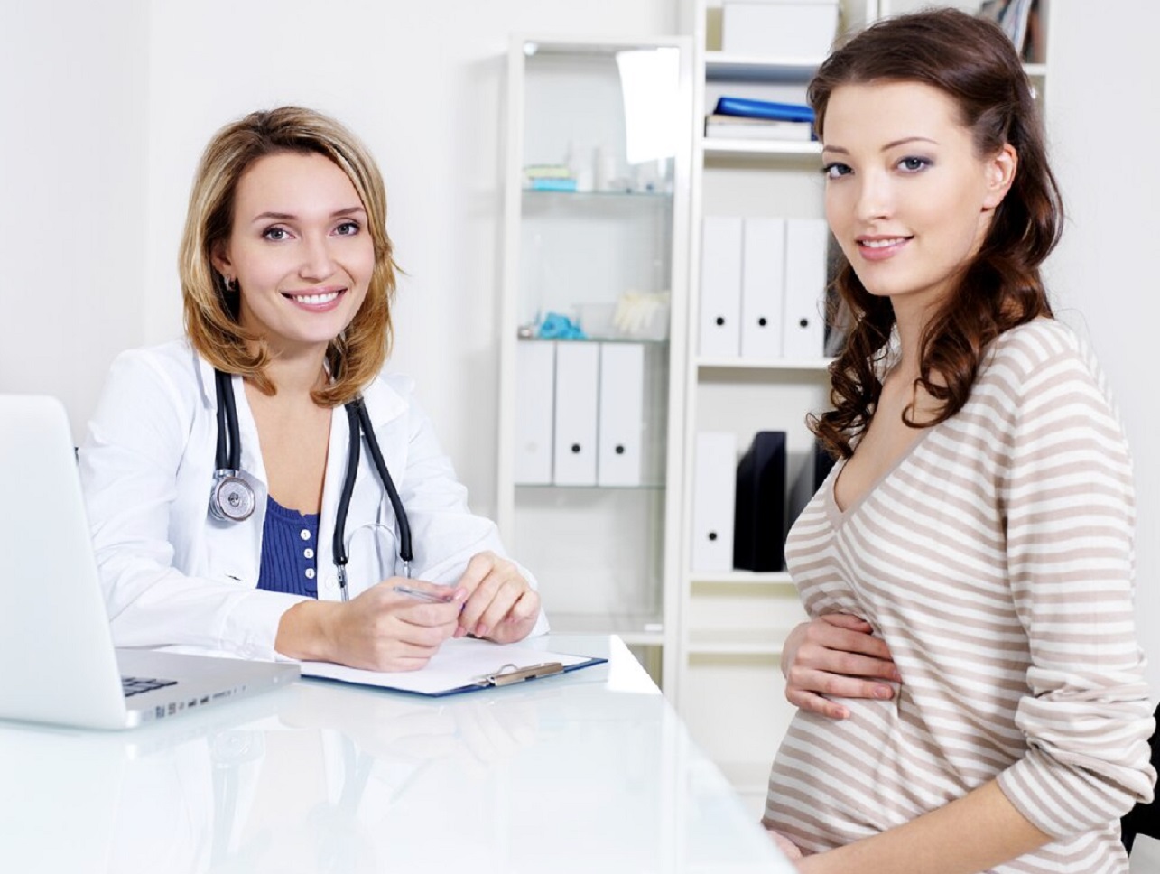 Young pregnant woman and smiling with doctor.