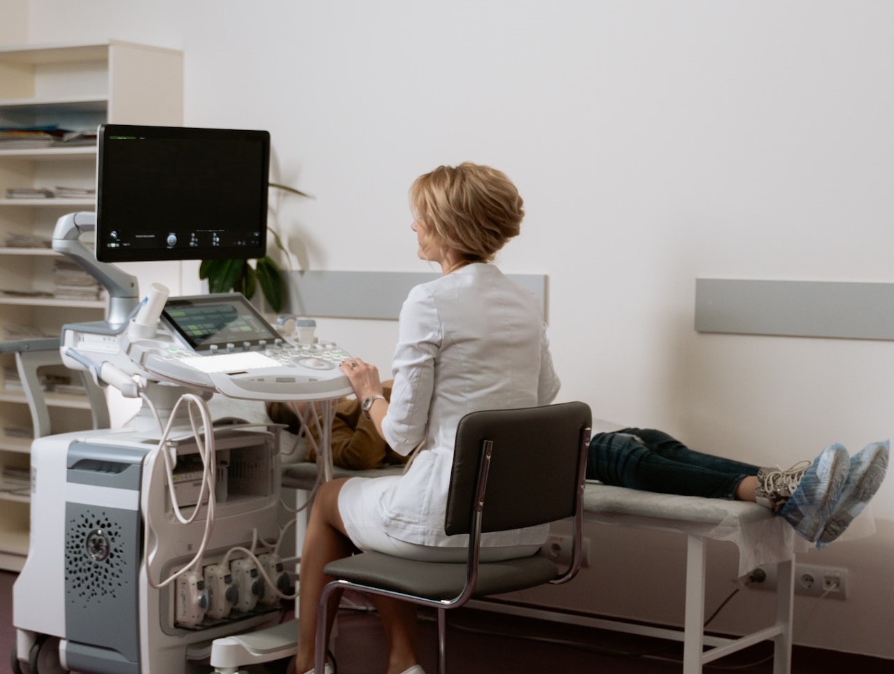 Young pregnant woman is laying on bed with female doctor in hospital.