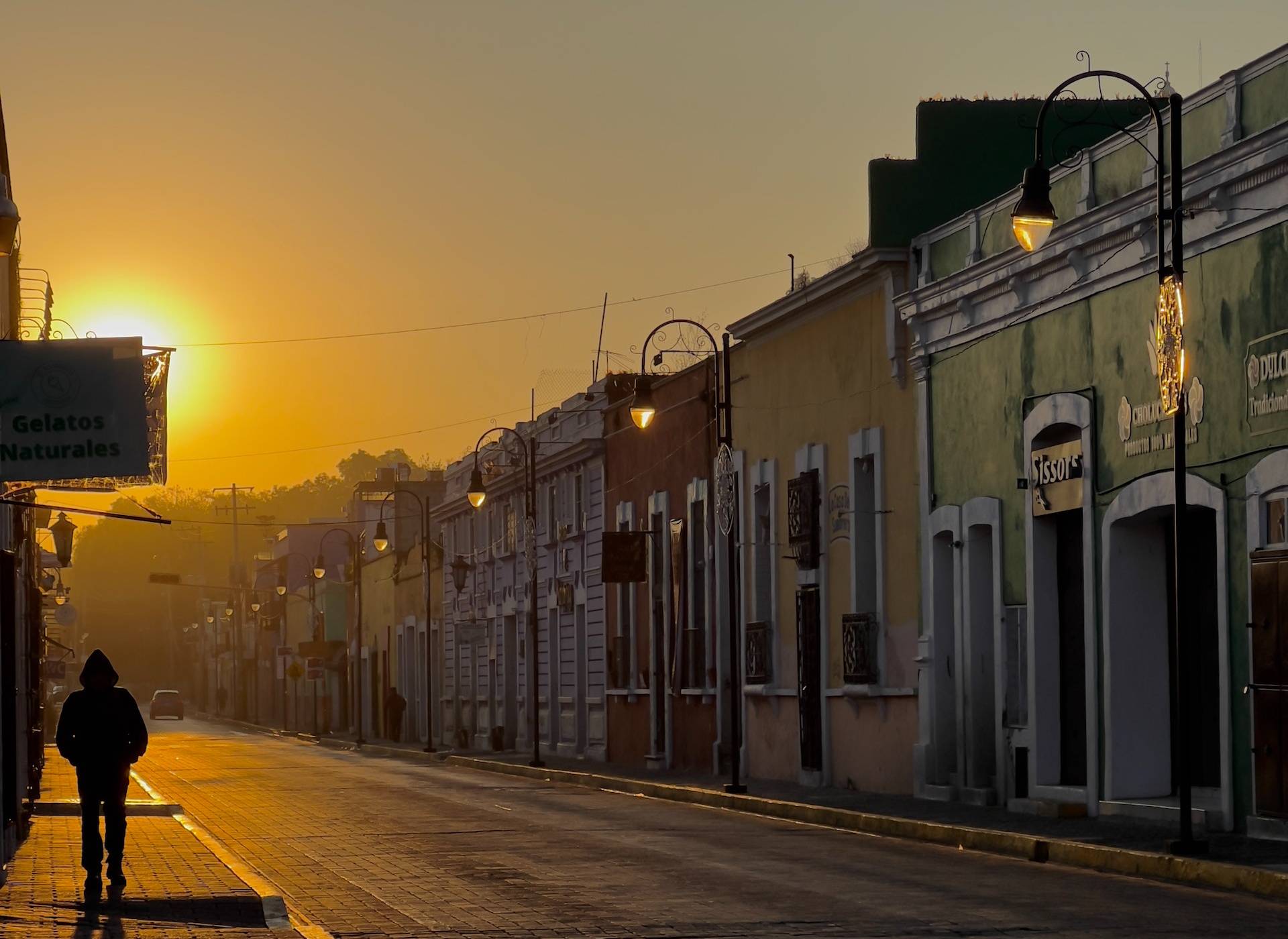 Person walking on sidewalk during sunrise in Mexican city