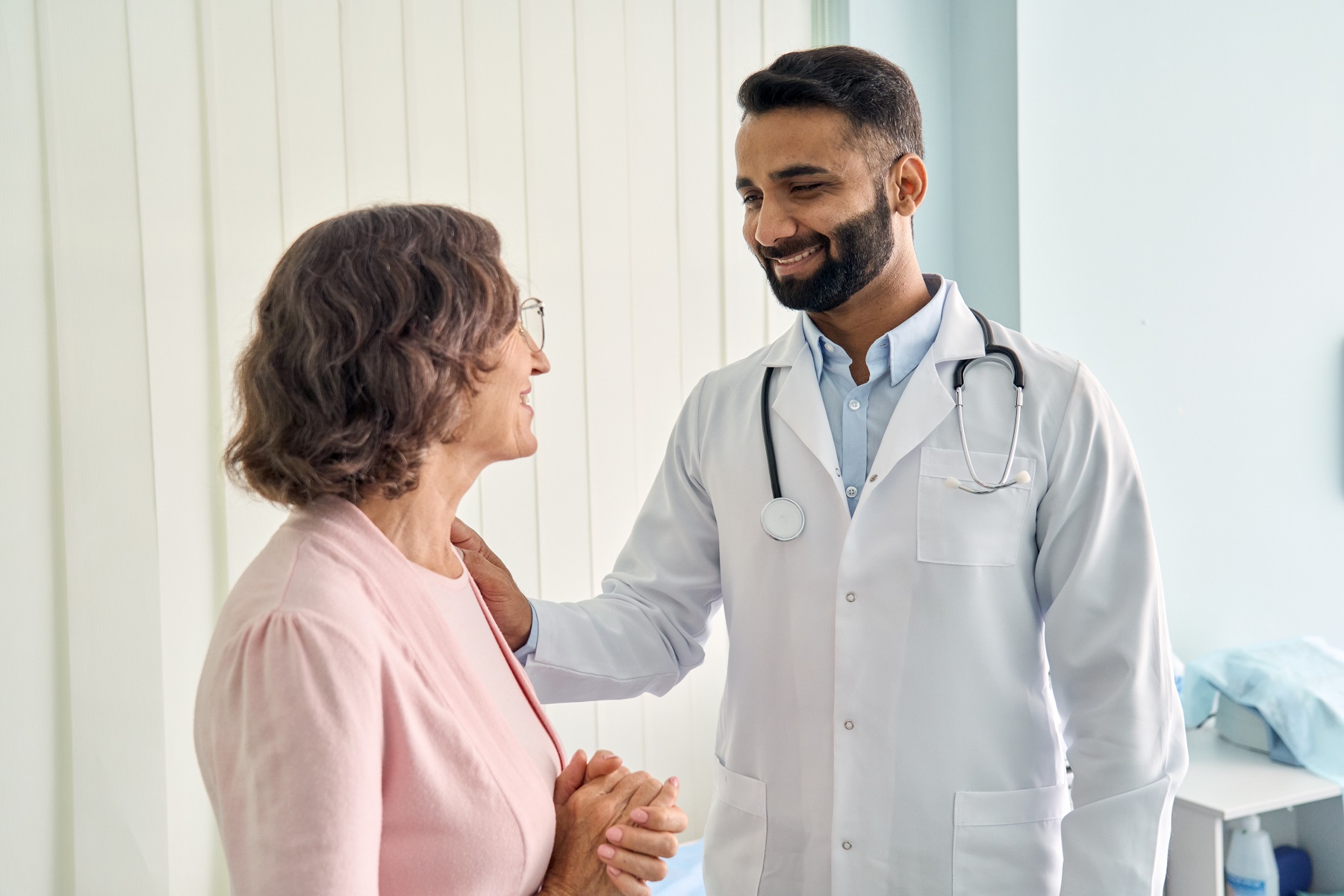 Doctor in white coat has consulting with older senior female patient in hospital.