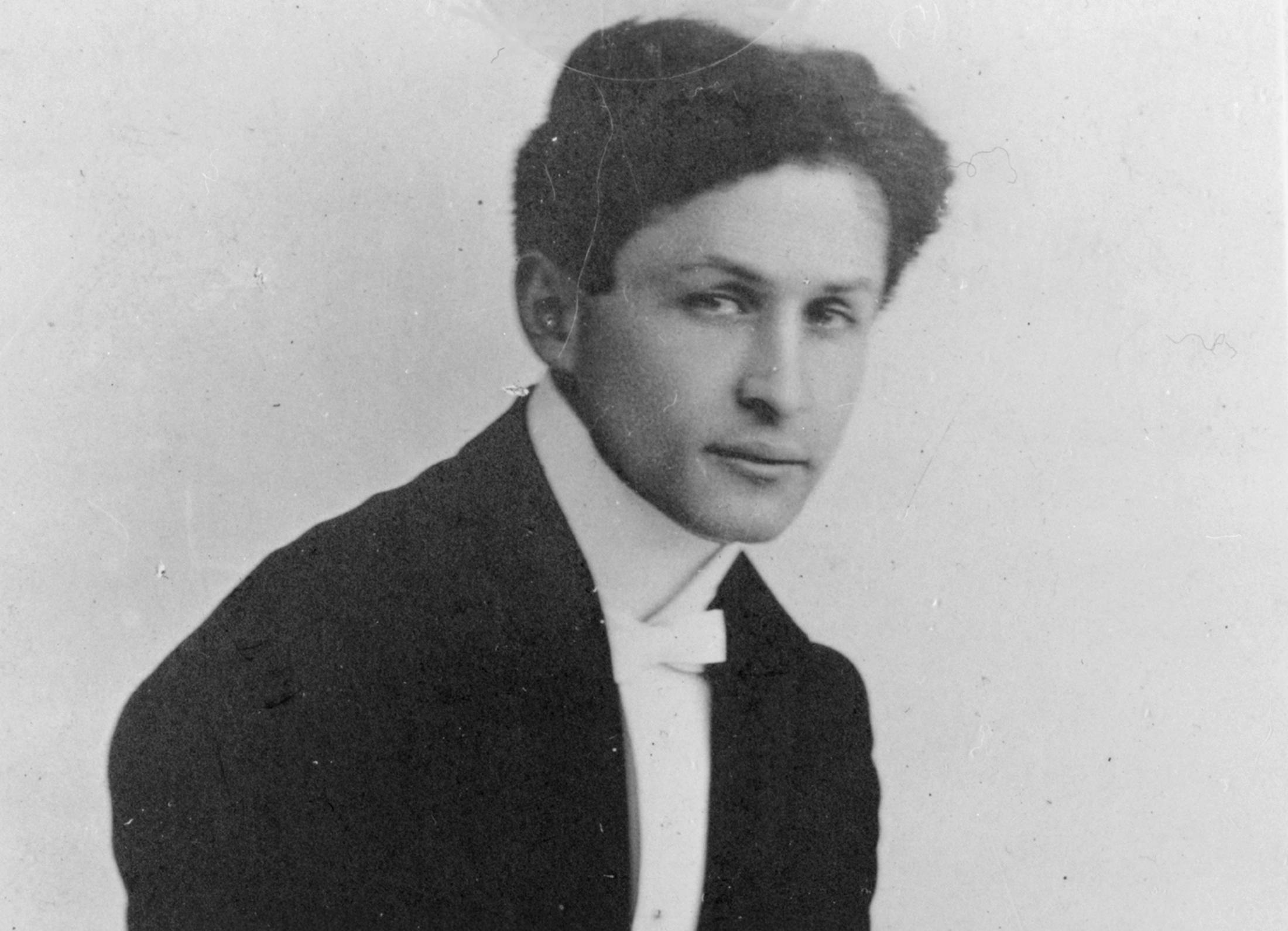Harry Houdini, circa 1905 full-length portrait, standing, facing right, in chains in suit