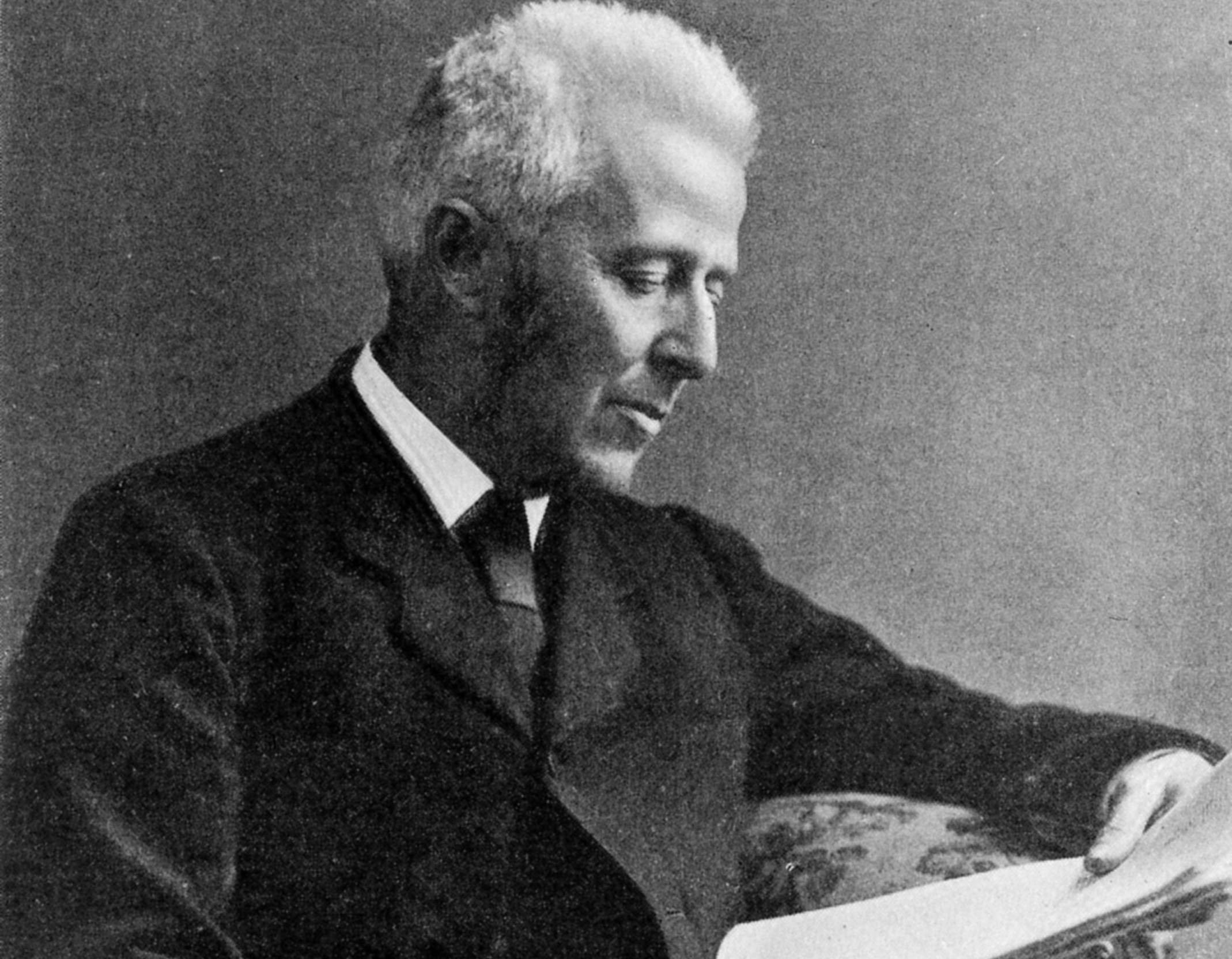 Joseph Bell sitting on a chair in black suit