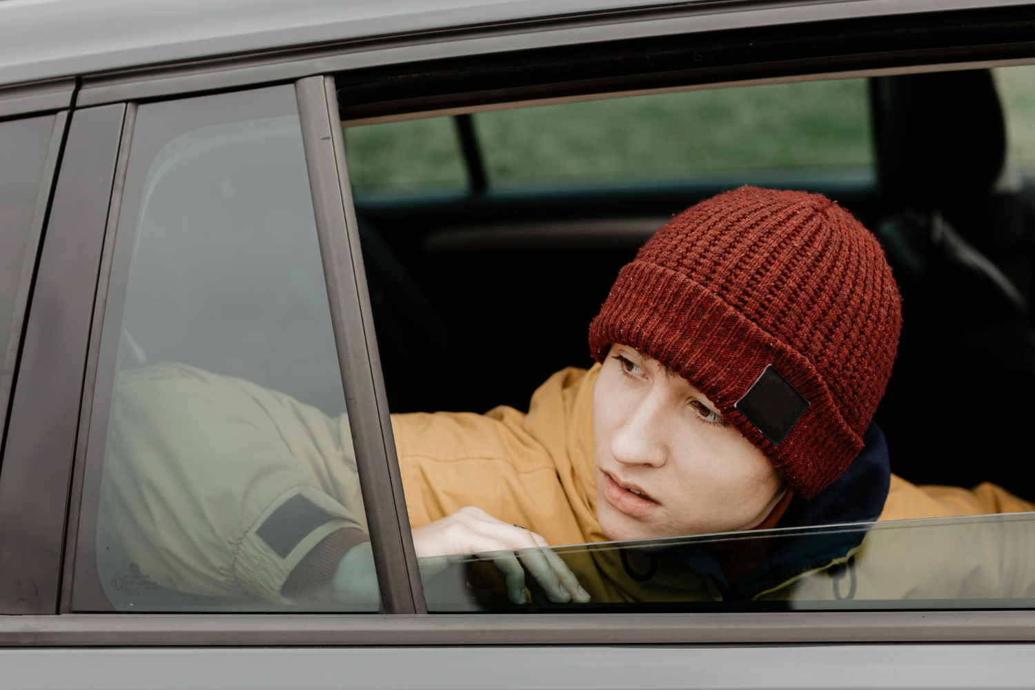 Young kid is waiting inside a car.