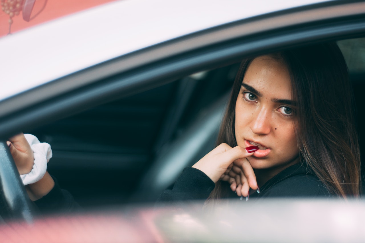 Young woman is looking from car window outside.