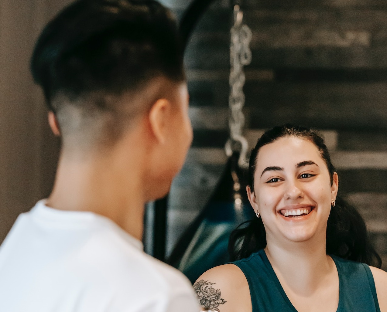 Young woman is smiling and is talking with young man in white shirt.