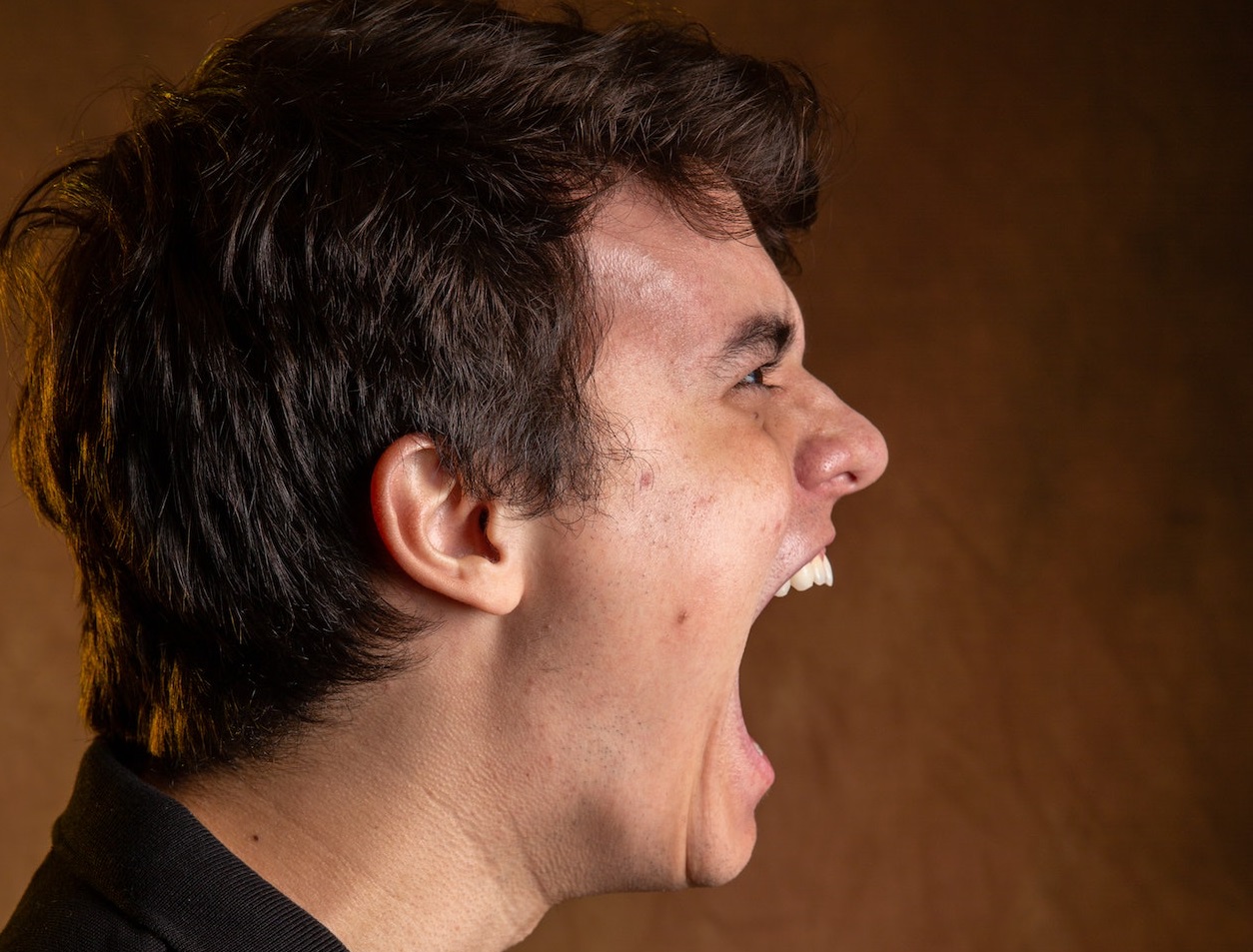 Side view of a man shouting.