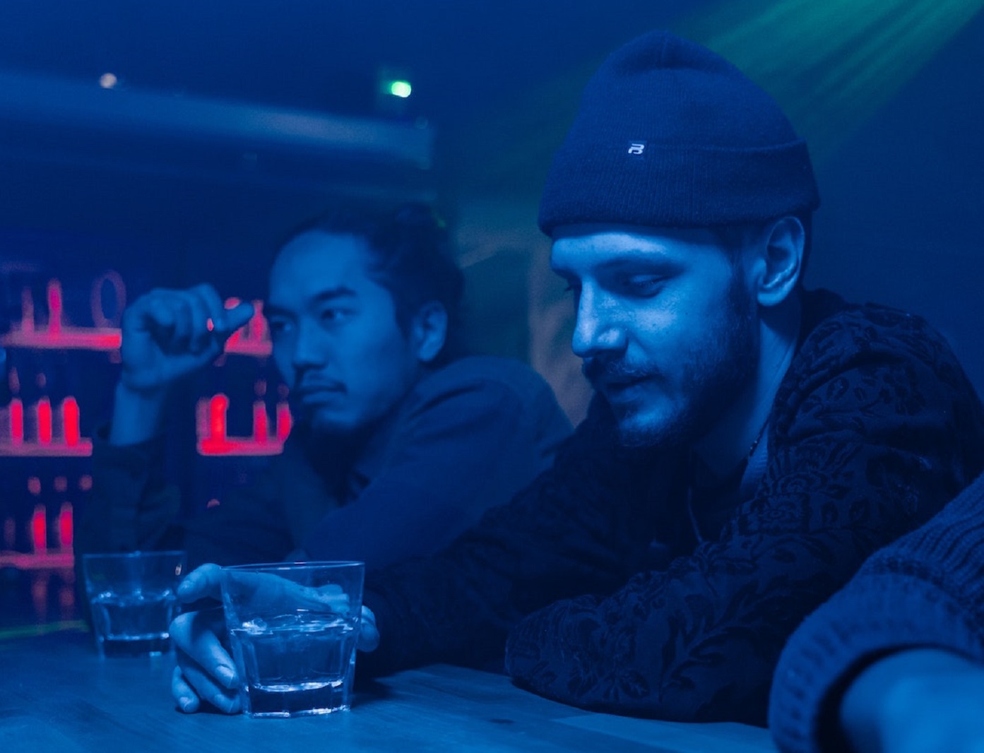 Man is seating at bar with other people.