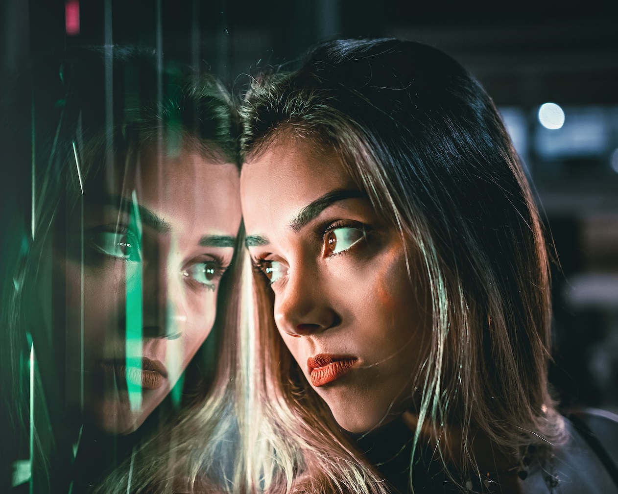 Young blonde woman is standing by the window.