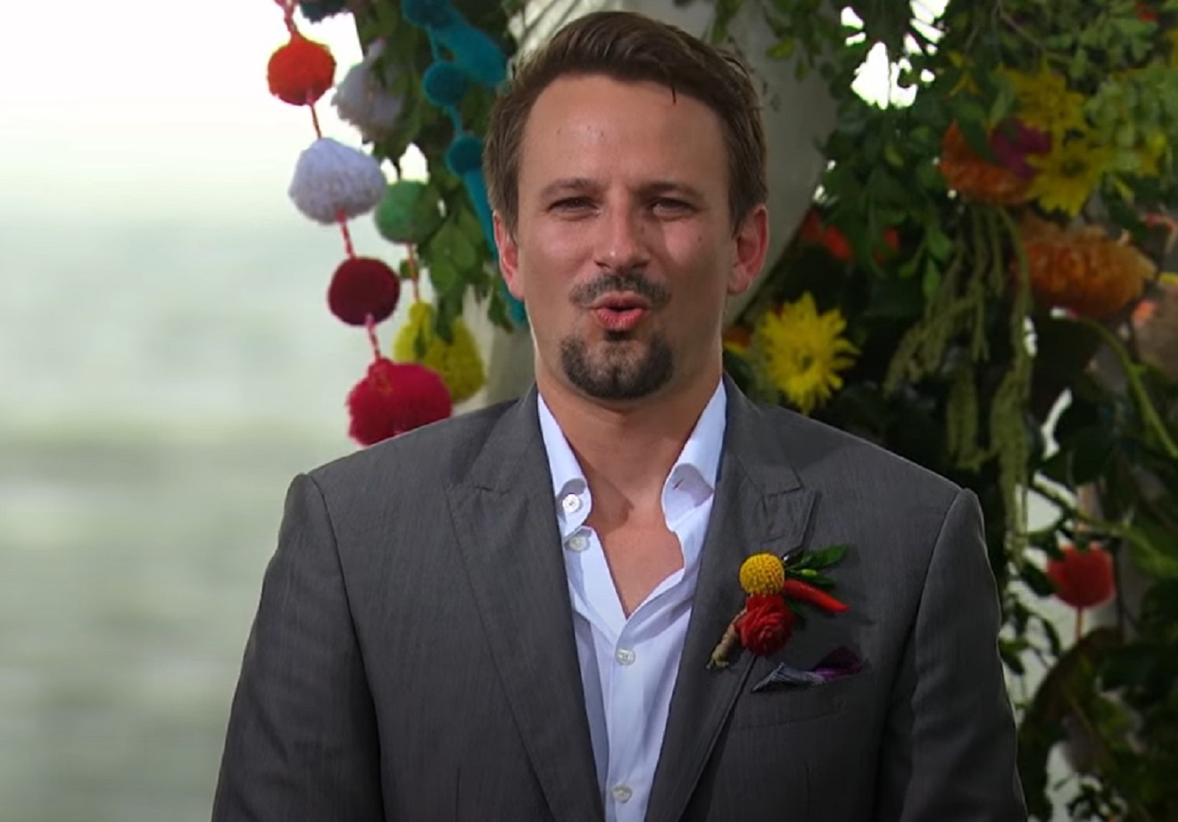 Screenshot: Evan Bass is looking at front with surprised face - from Bachelor in Paradise (American TV series)