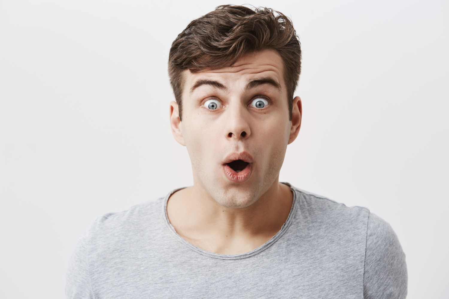 Young man is looking at camera with surprised face.