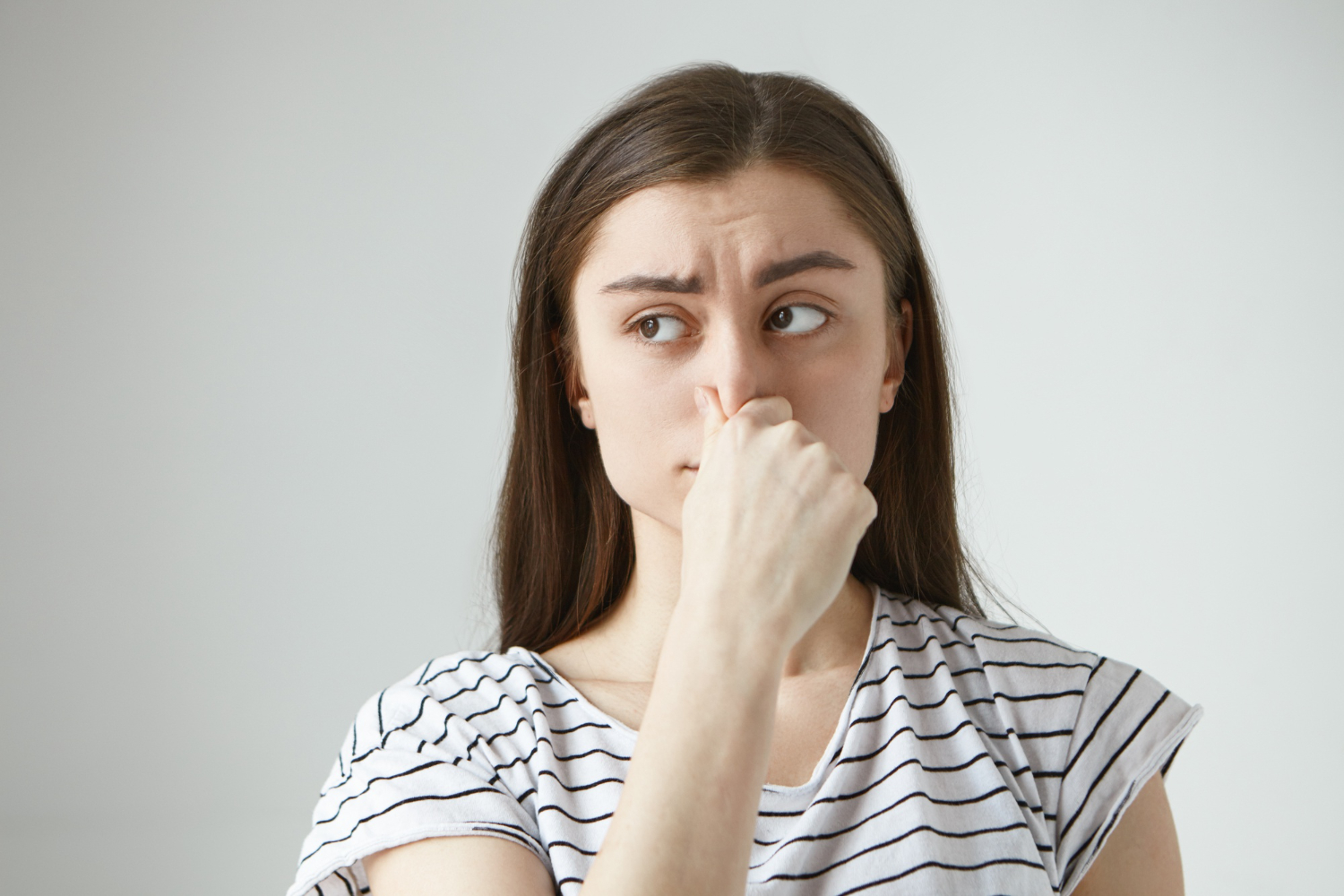 A girl is looking at side and holding her nose.