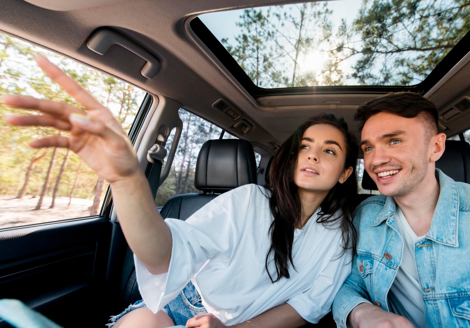 Young couple is seating in the car and looking outside.