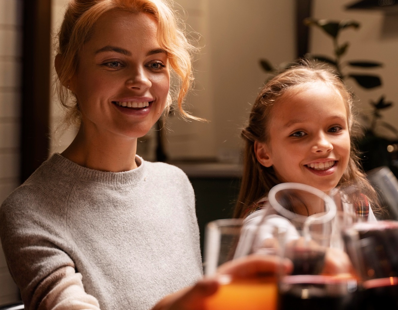 Woman is smiling and making a toast at dinner seating next to her daughter.