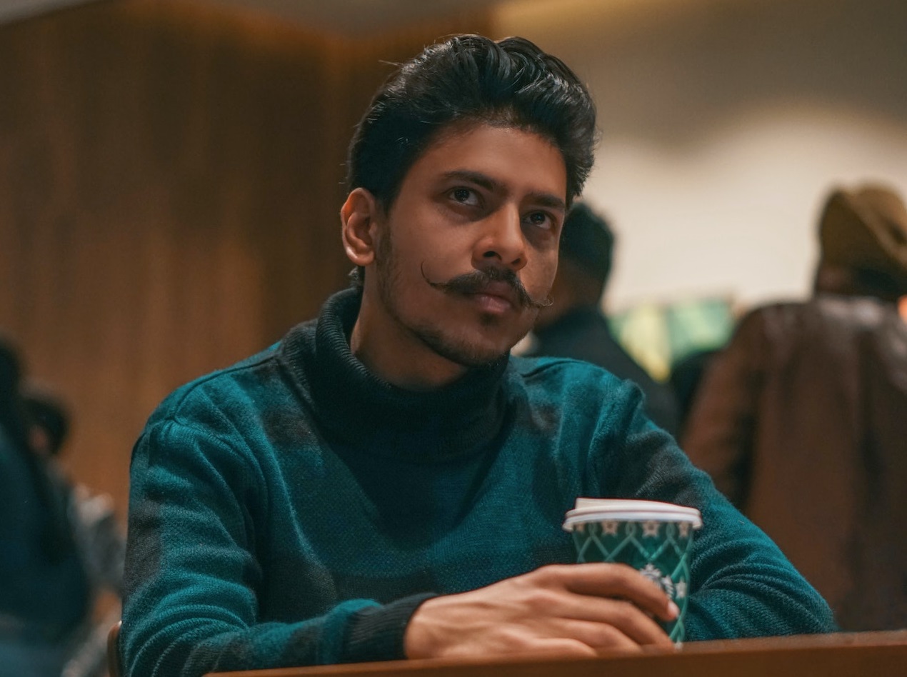 Young man is seating alone and drinking coffee.