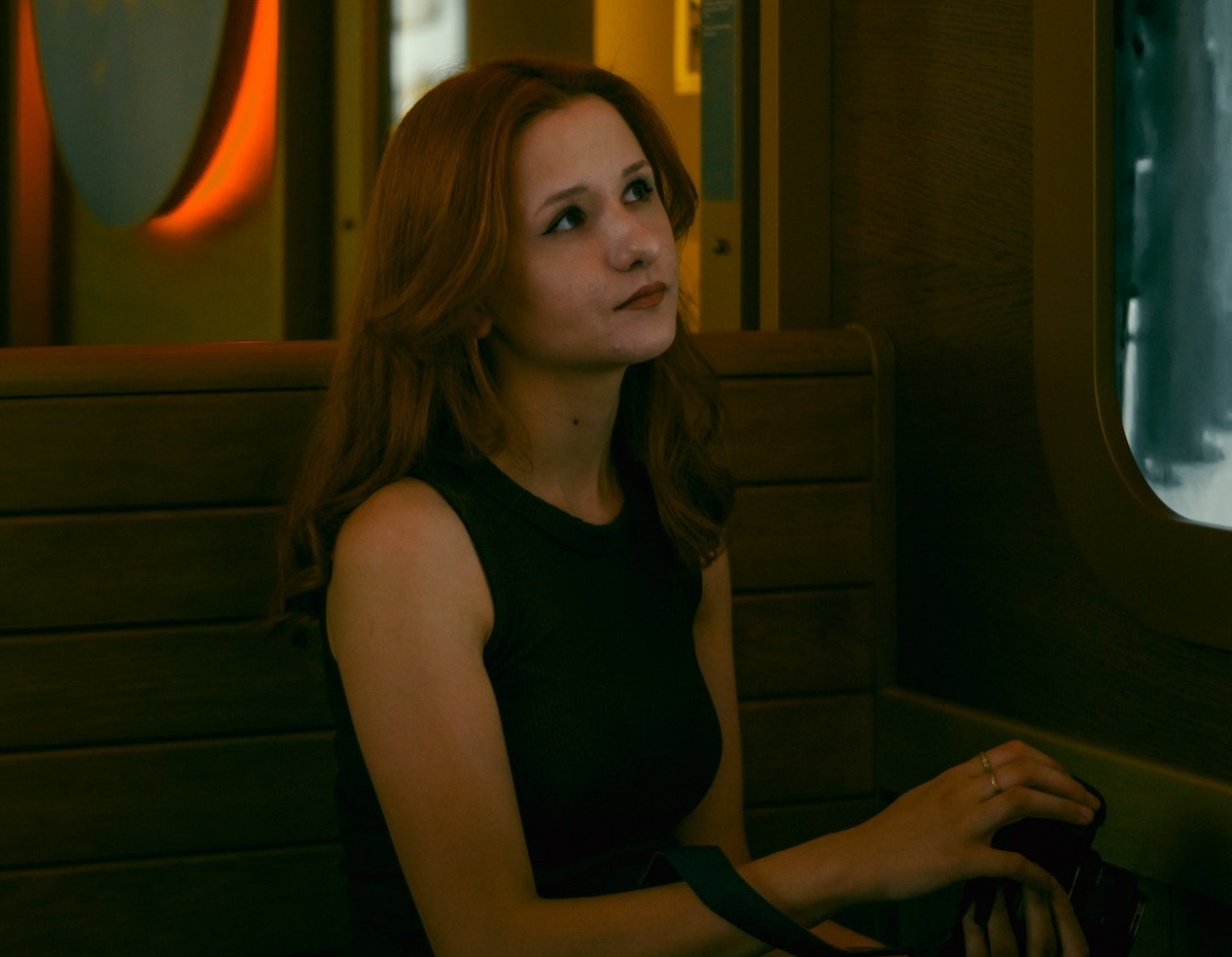 Young woman is seating alone at restaurant with sad face.