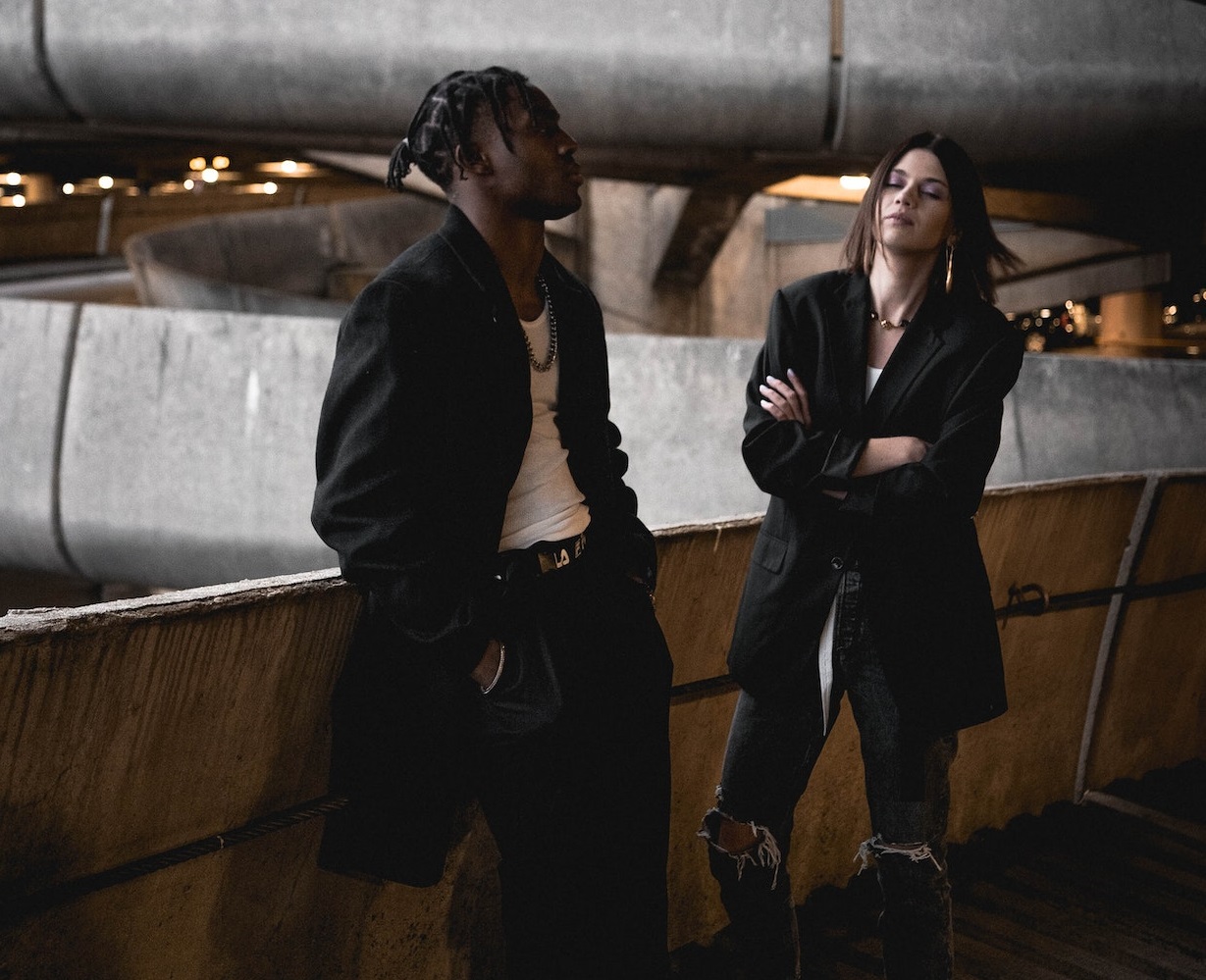 Woman is standing and looking at young black man who is looking at side upset.