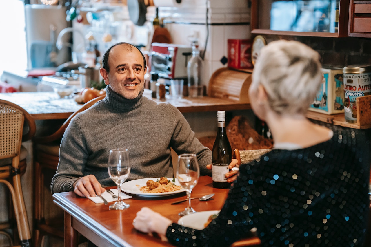 Man is smiling and having lunch with woman at restaurant.
