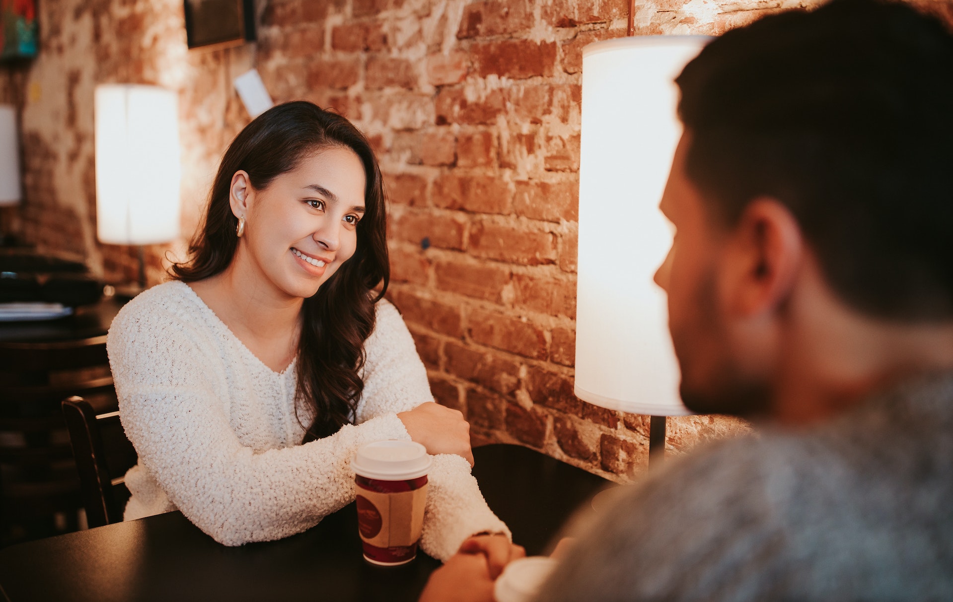 Young woman is having a coffee in coffee shop with man looking at her.