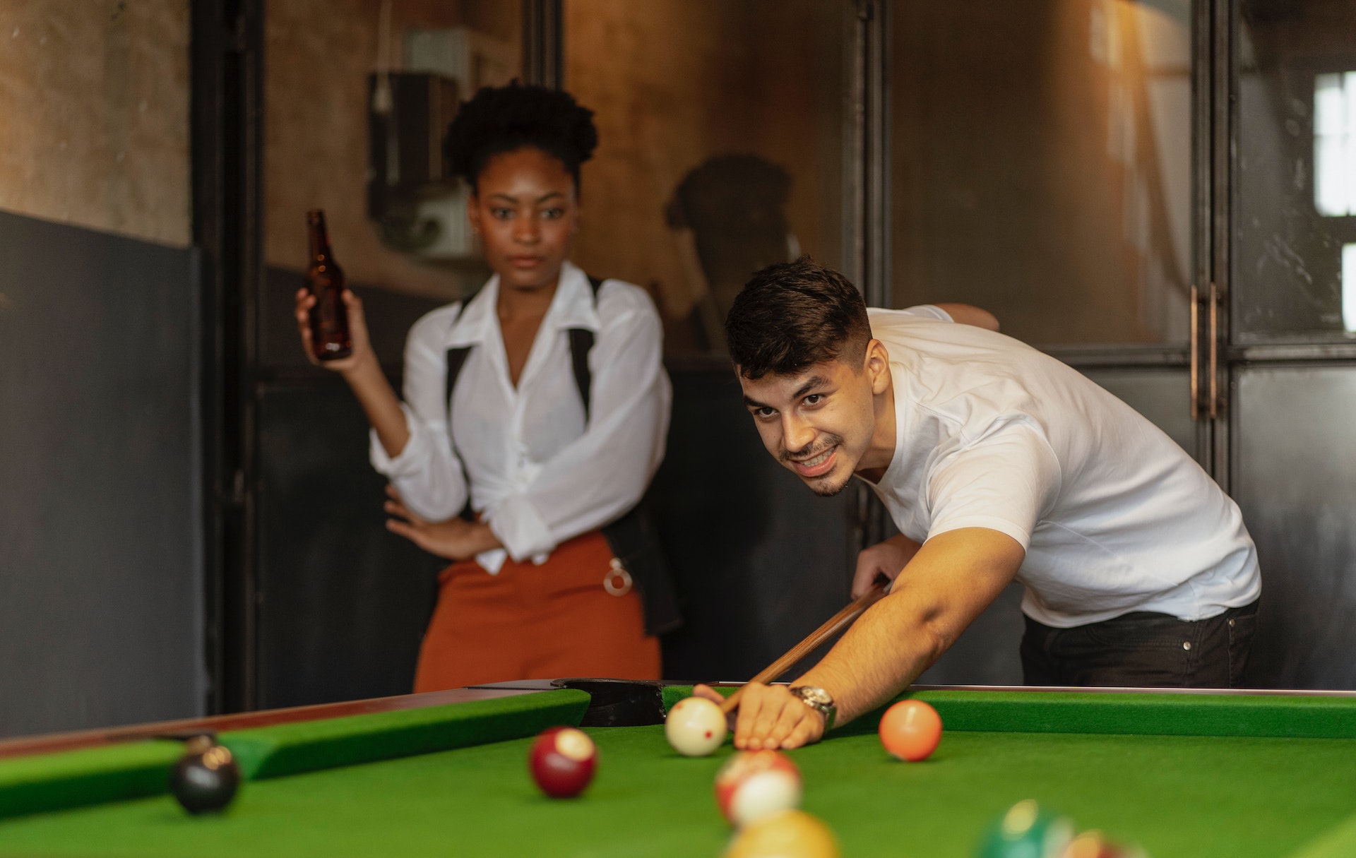 Woman is watching a man playing snooker.