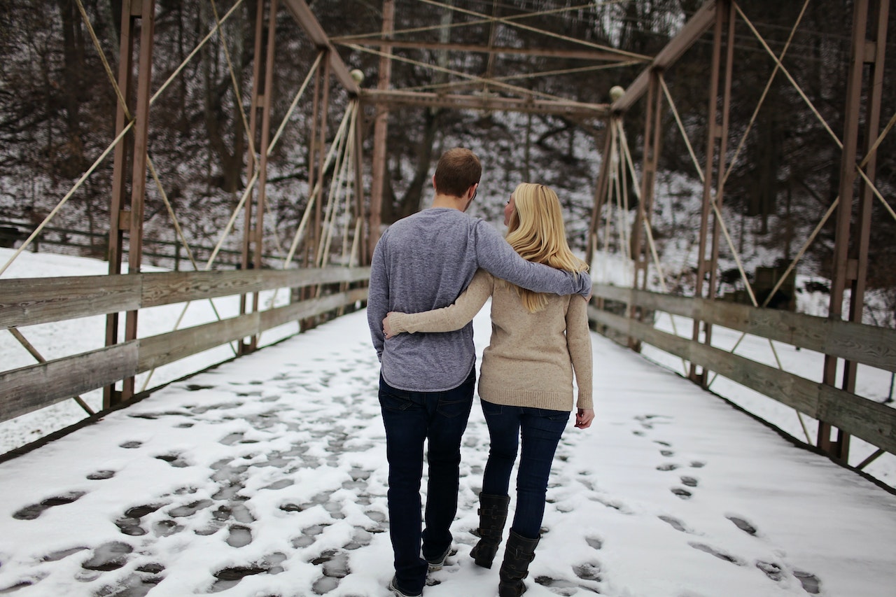 Young couple are walking outside on a road with snow.