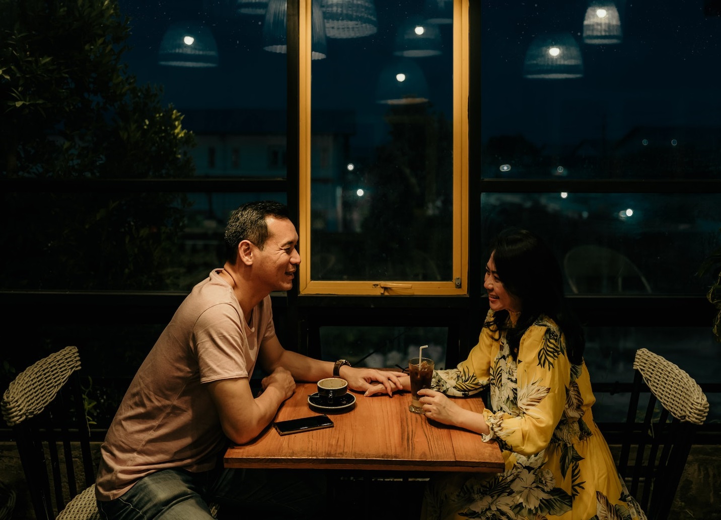 Young woman is seating on the table with man ,drinking coffee together and smiling.