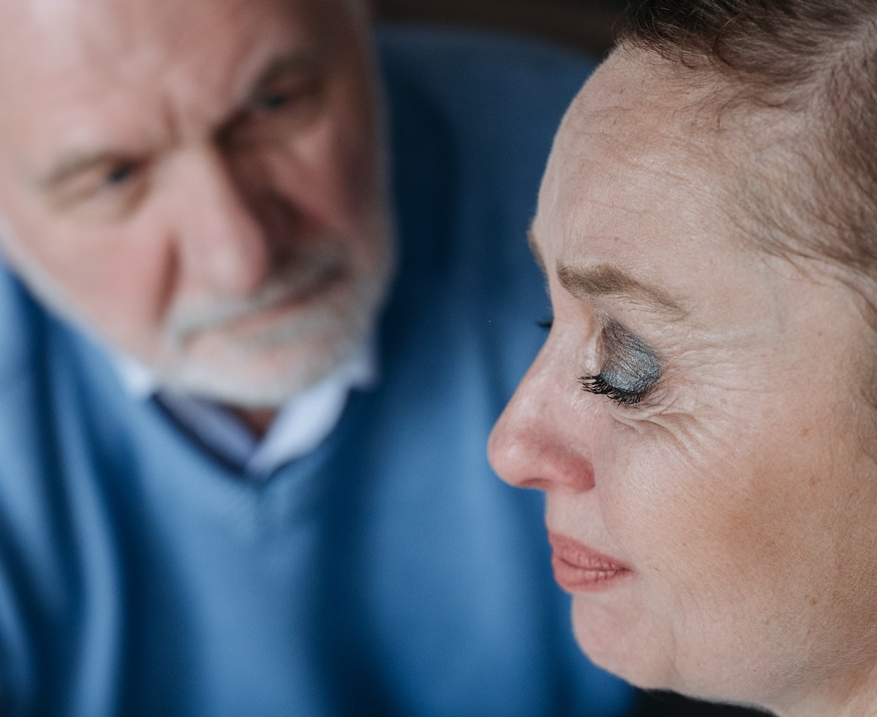 Man is standing next to a crying woman and looking at her.