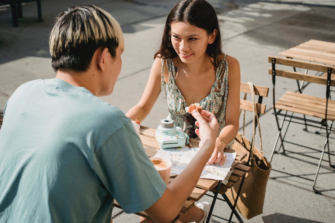 Young couple are seating and having a breakfast outdoor