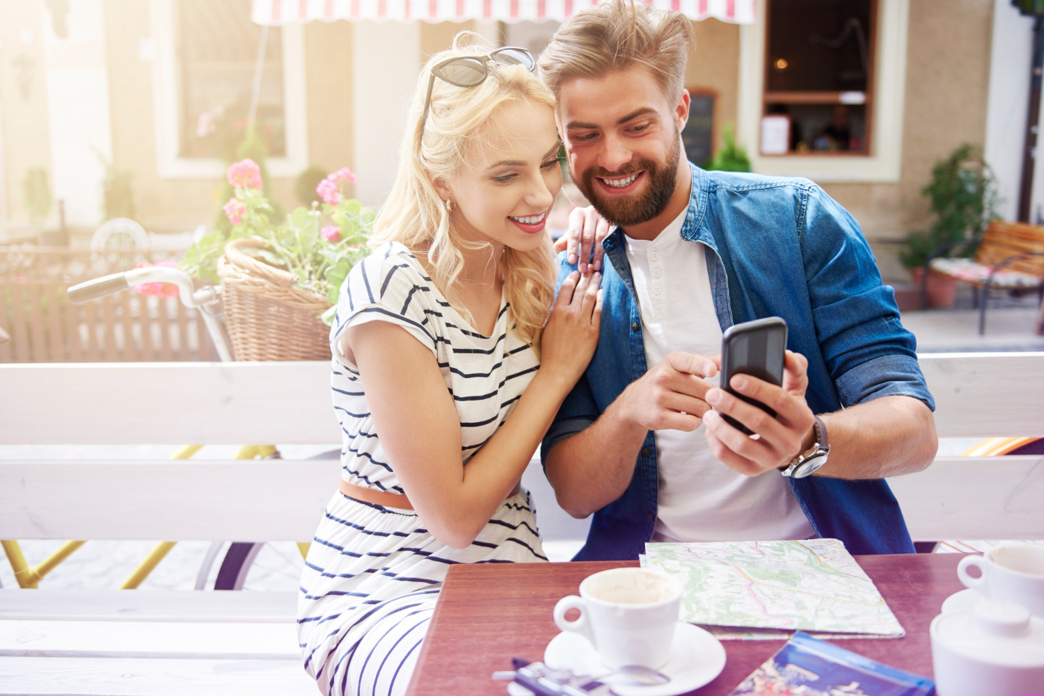 Couple are drinking coffee and looking at cell phone.