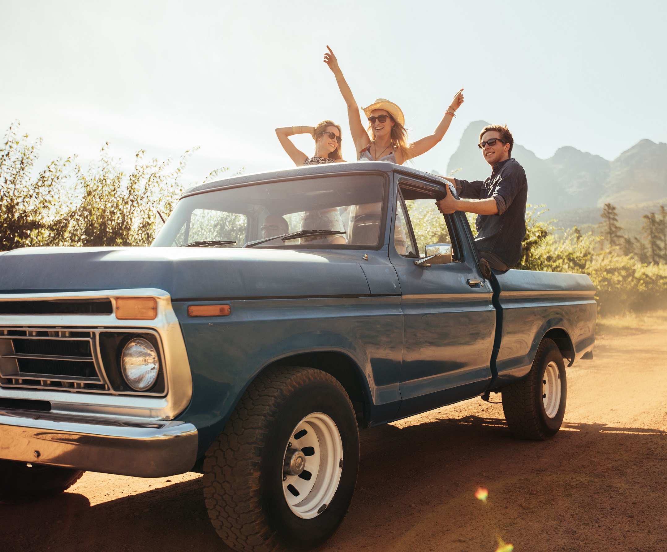 People are dancing in the back of a blue pick up truck.