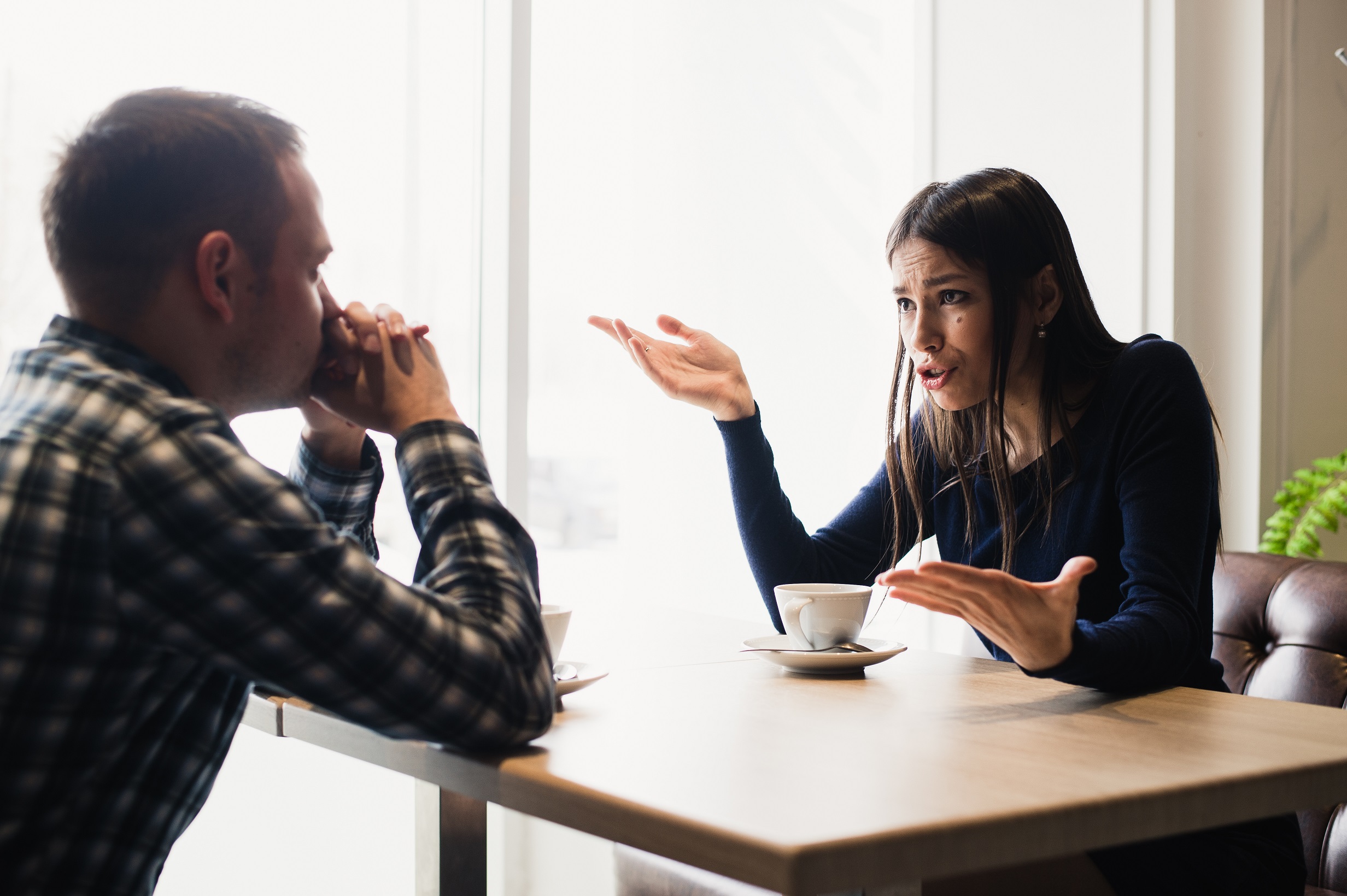 Young woman is arguing with a man seating at restaurant.