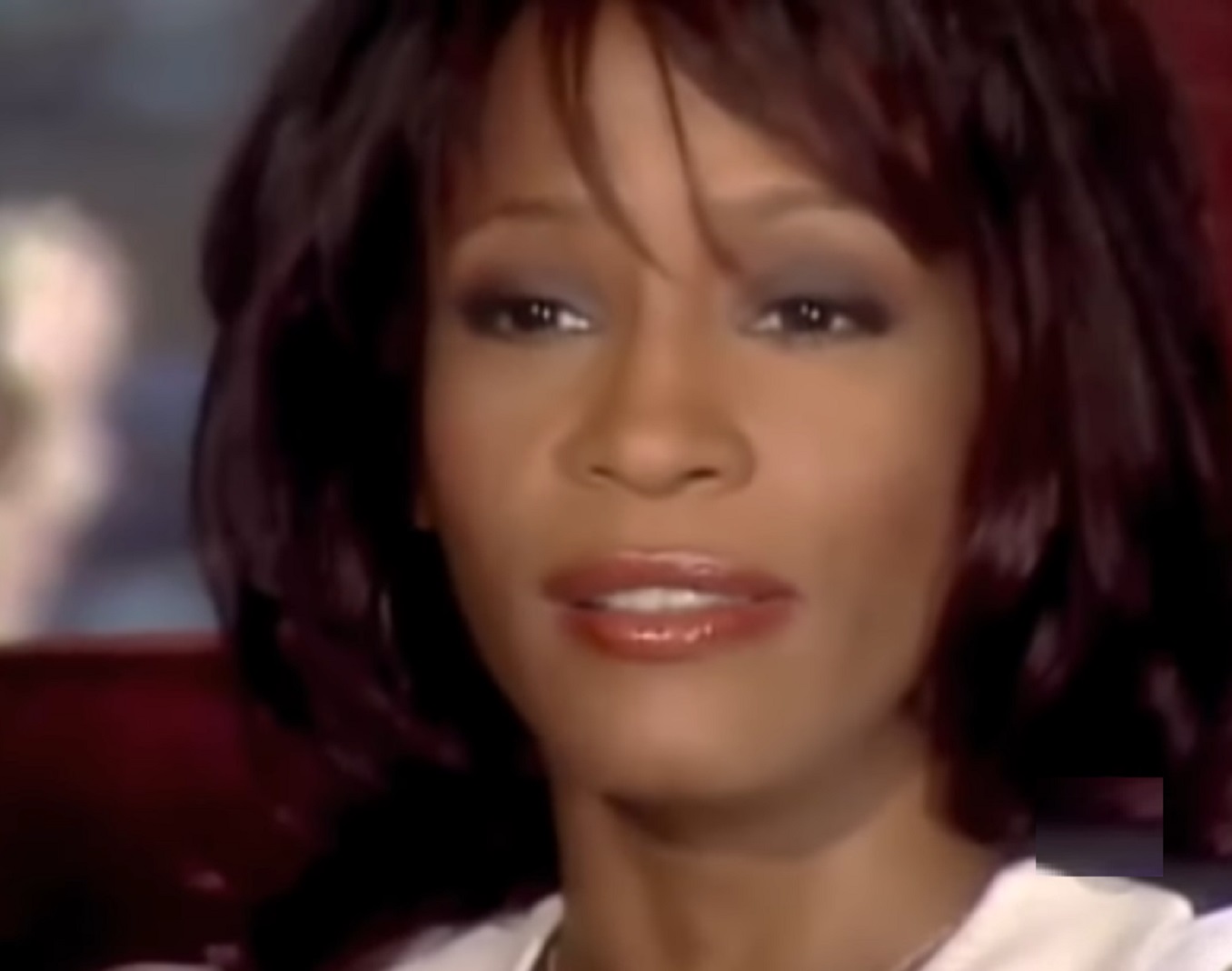 Screenshot of Whitney Houston wearing white shirt is talking - from Whitney (2018)