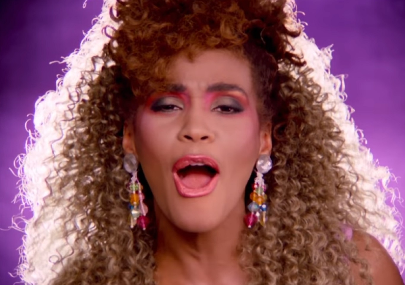 Screenshot of Whitney Houston with colorful earrings is singing - from Whitney (2018)
