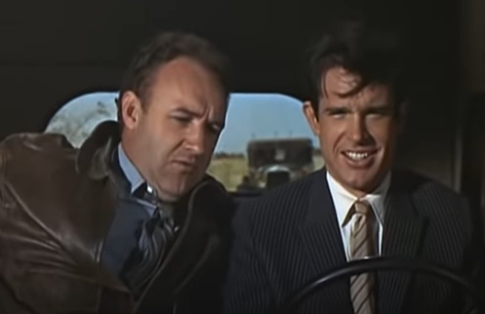 Gene Hackman in  Bonnie and Clyde wearing a jacket and tie speaking with Clyde