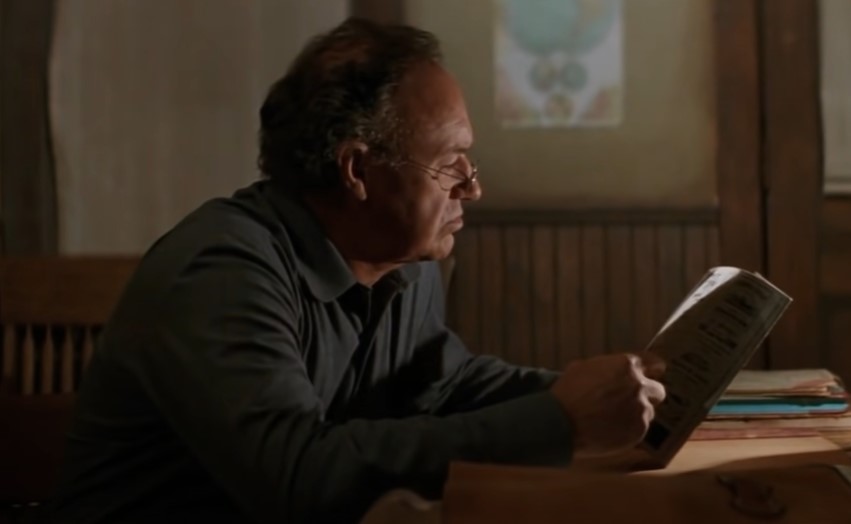 Gene Hackman  in Unforgiven sitting at a desk in blue shirt
