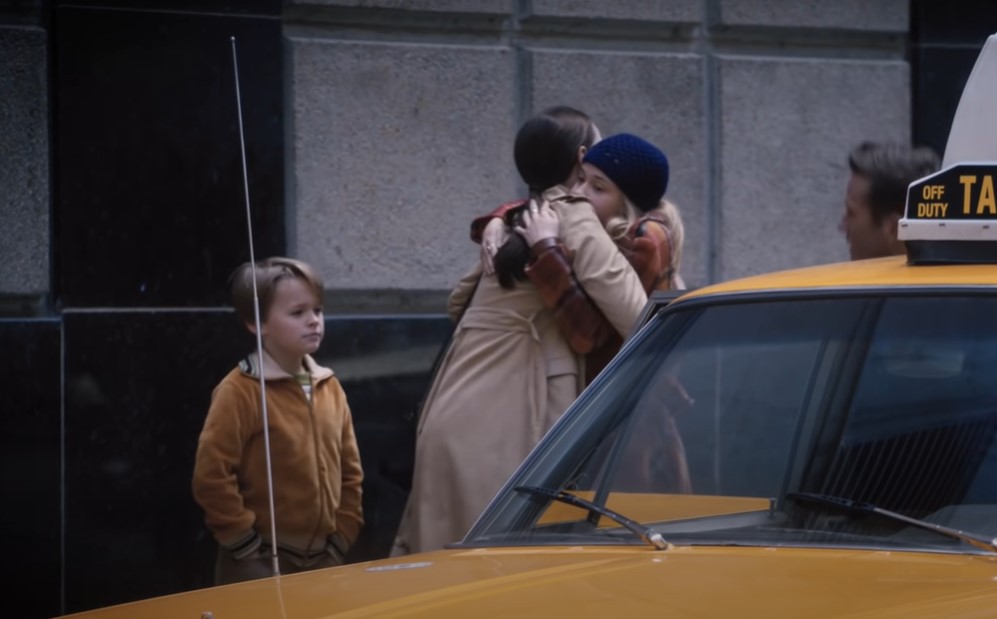Felicity Jones as Ruth Bader Ginsburg in trench coat in front of a taxi with her children