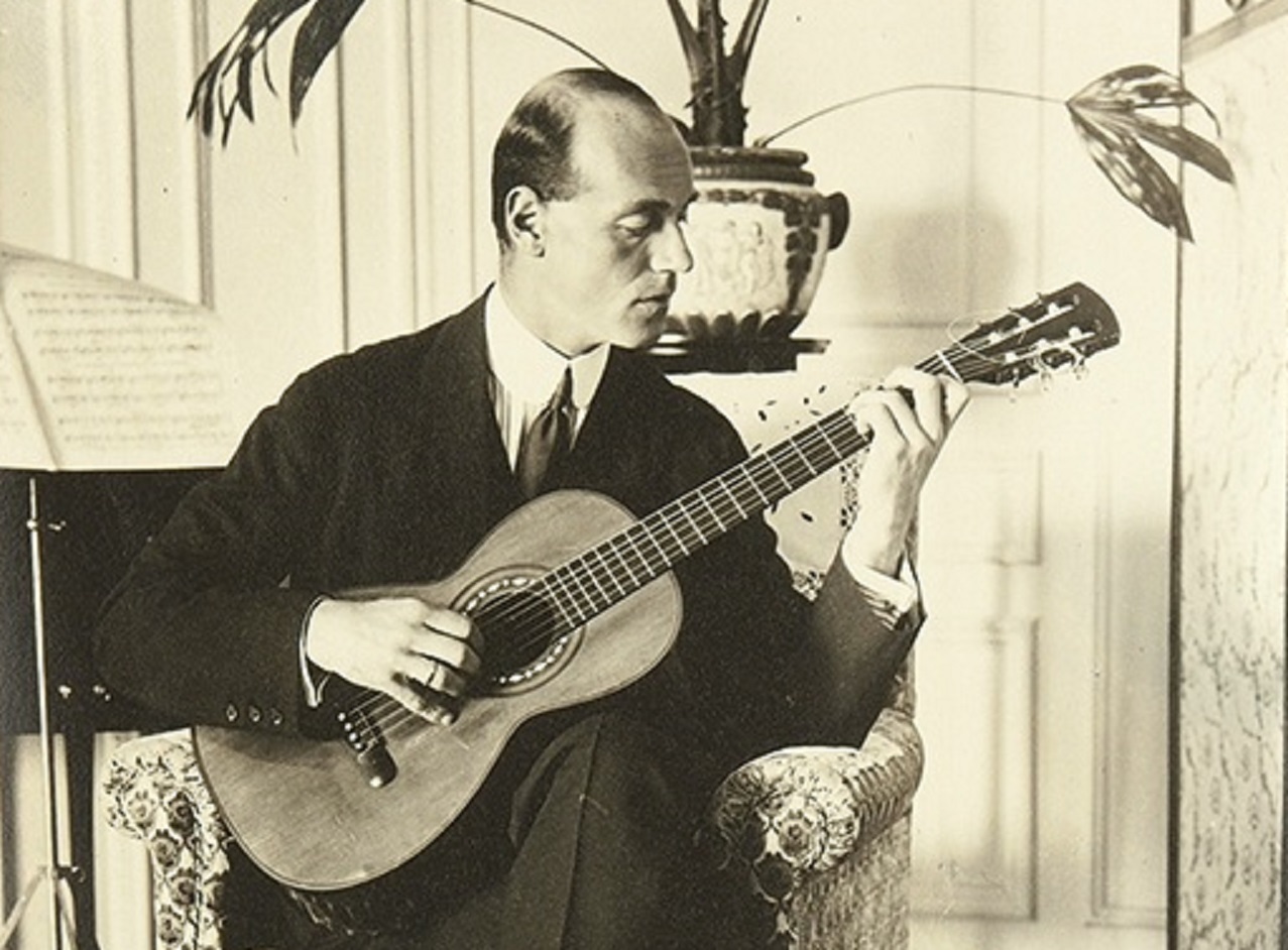Grand Duke Mikhail Alexandrovich Romanov wearing black suit is playing  a guitar - circa 1912-1914
