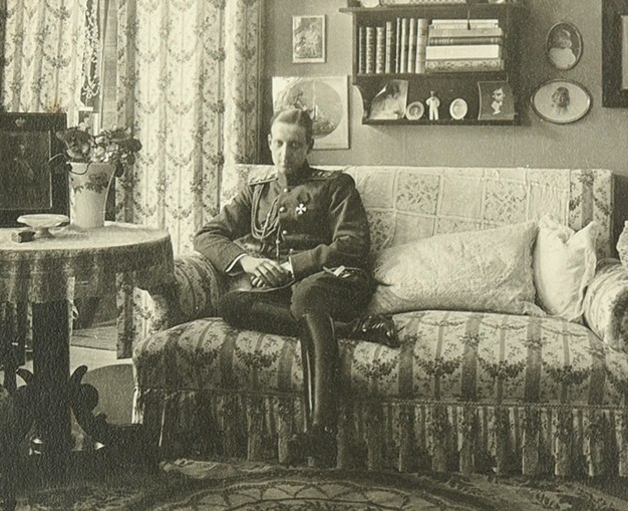 Grand Duke Mikhail Alexandrovich Romanov is seating on the bed inside a room - circa 1912 - 1914