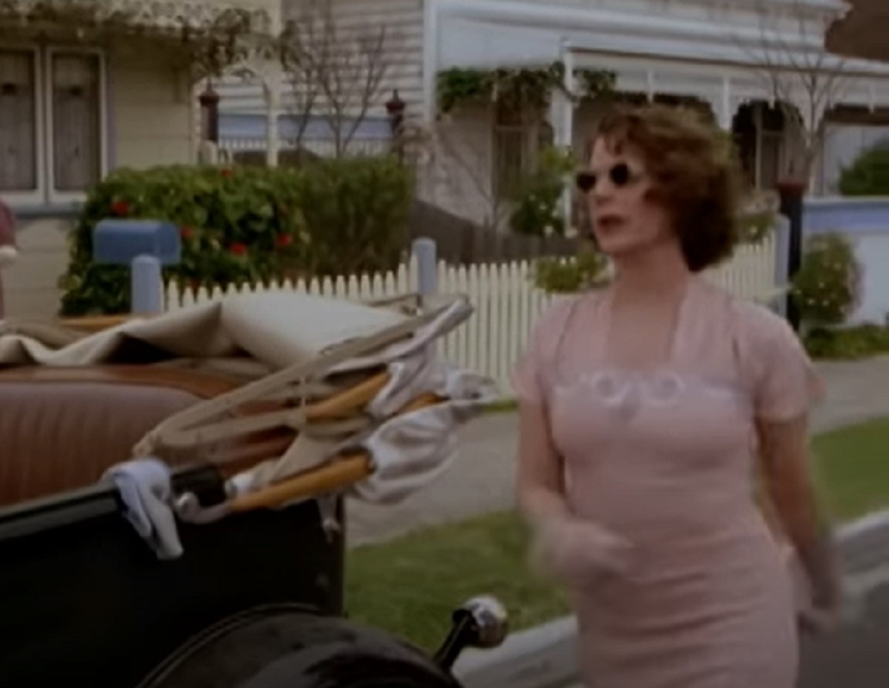 Screenshot: Gladys Pearl Baker (Patricia Richardson) wearing pink dress is walking outside - from Blonde (2001)
